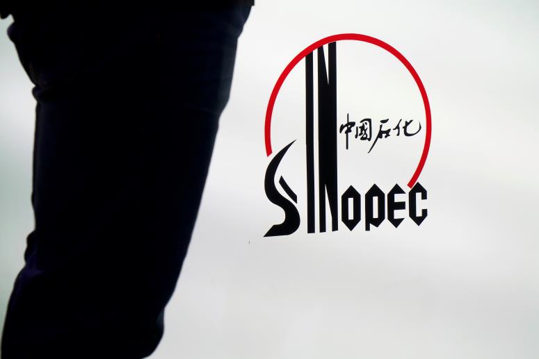 A man stands next to a logo of Sinopec, or China Petroleum and Chemical Corporation, at an expo on rubber technology in Shanghai, China September 19, 2018. Picture taken September 19, 2018. REUTERS/Stringer 