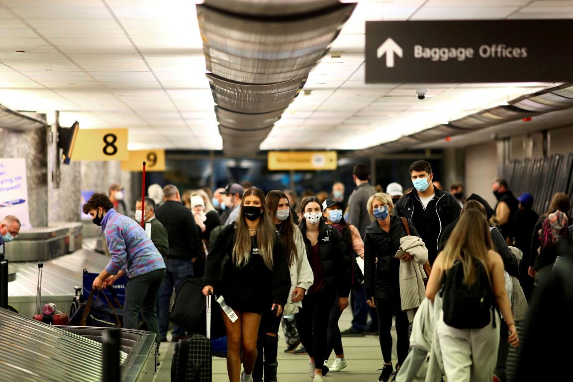 Travelers wearing protective face masks to prevent the spread of the coro<em></em>navirus disease (COVID-19) reclaim their luggage at the airport in Denver, Colorado, U.S., November 24, 2020.  REUTERS/Kevin Mohatt