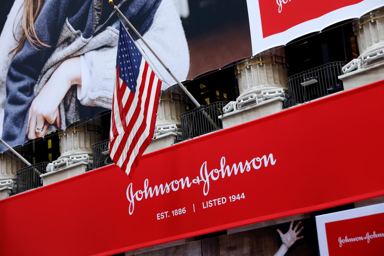 The U.S. flag is seen over the company logo for Johnson & Johnson to celebrate the 75th anniversary of the company's listing at the New York Stock Exchange (NYSE) in New York, U.S., September 17, 2019. REUTERS/Brendan McDermid/File Photo