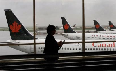 A passenger walks past several Air Canada jets at Vancouver Internatio<em></em>nal Airport, September 26, 2001. REUTERS/Andy Clark