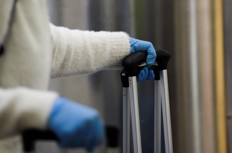 A passenger wearing gloves hold her luggage, as part of the security measures due to the outbreak of the coro<em></em>navirus (COVID-19), at Jose Joaquin de Olmedo Internatio<em></em>nal Airport in Guayaquil, Ecuador March 13, 2020. REUTERS/Santiago Arcos/file photo