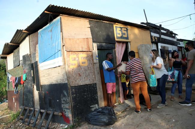 Residents of Cidade de Deus slum, receive food and bread from members of the Institute doAcao, which was produced at the Santuario de Nossa Senhora de Fatima (Sanctuary of Our Lady of Fatima), amid the coro<em></em>navirus disease (COVID-19) outbreak, in Rio de Janeiro, Brazil, June 24, 2021. REUTERS/Ricardo Moraes