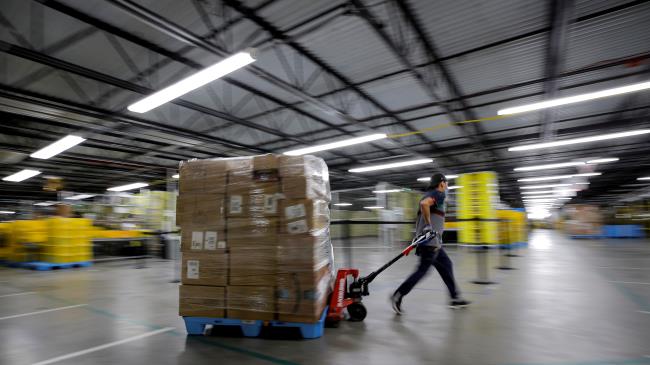 An employee pulls a cart full of items at Amazon's JFK8 distribution center in Staten Island, New York, U.S. November 25, 2020.  REUTERS/Brendan McDermid.     TPX IMAGES OF THE DAY/File Photo