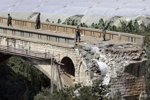 Men standing on a bomb damaged bridge.