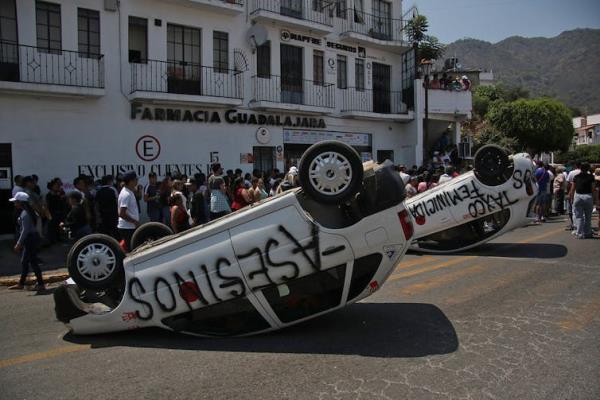 An overturned car on a street in a protest against violent crime.