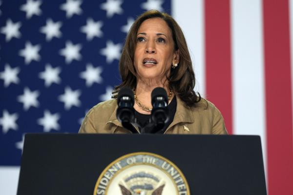 A woman speaks at a podium in front of an American flag