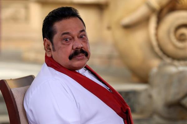 A man with a thick black moustache looks past the camera