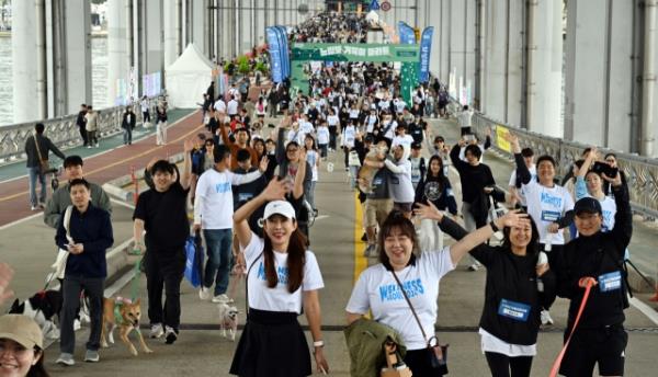 Participants of the Slow Marathon with Pets and their companion pets walk along the Jamsu Bridge -- a submersible bridge co<em></em>nnecting Yo<em></em>ngsan and Seocho -- on Sunday. (Park Hae-mook/The Korea Herald)