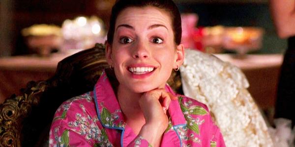 Anne Hathaway as Mia smiling with a hand to her chin in The Princess Diaries 2