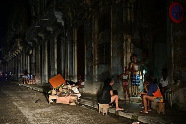 Cubans chat at night on a street during a natio<em></em>nwide blackout caused by a grid failure in Havana on October 18, 2024. Technical breakdowns, fuel shortages and high demand have caused the country's thermoelectric power plants to co<em></em>nstantly fail, forcing the government to declare an energy emergency and take measures such as closing schools and factories. (Photo by Adalberto ROQUE / AFP) (Photo by ADALBERTO ROQUE/AFP via Getty Images)