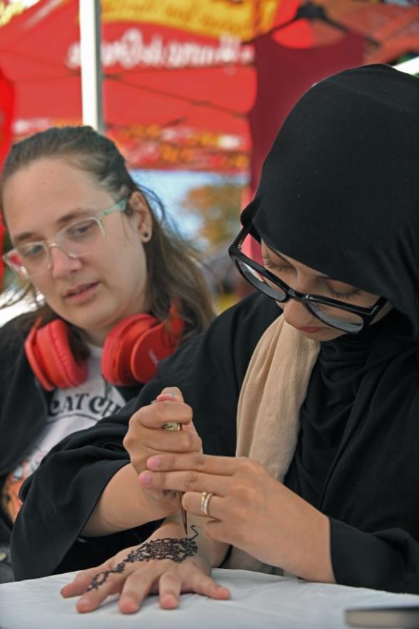 Artist Hajar Ferry, right, makes a Henna design on the hand of Matt Matthews during the 61st Havre de Grace Art Show on the waterfront at Tydings Memorial Parks. (Kenneth K. Lam/Staff)