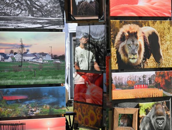 Braxton Richardson IV, of Silver Springs, is reflected in a glossy photograph as he checks out Steve Smith's pictures during the 61st Havre de Grace Art Show on the waterfront at Tydings Memorial Parks. (Kenneth K. Lam/Staff)