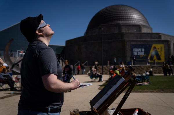 Vincent Lotesto paints the changing stages of solar eclipse near the Adler Planetarium, on April 8, 2024. (E. Jason Wambsgans/Chicago Tribune)