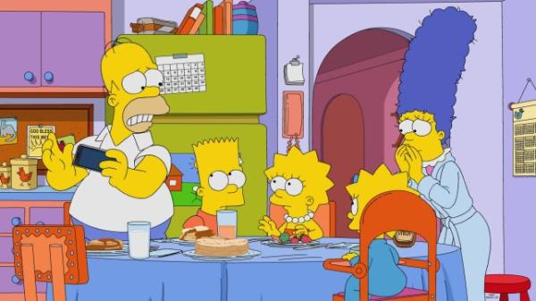 The Simpsons family Homer, Bart, Lisa, Marge and Maggie around a blue dining table in their kitchen