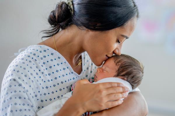 A woman kisses her newborn.