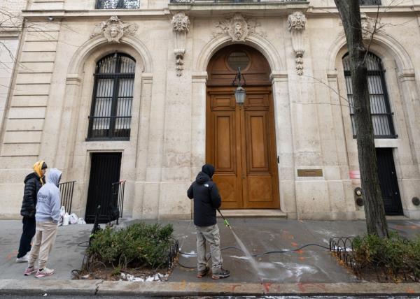 A picture showing three workers outside the graffitied building.