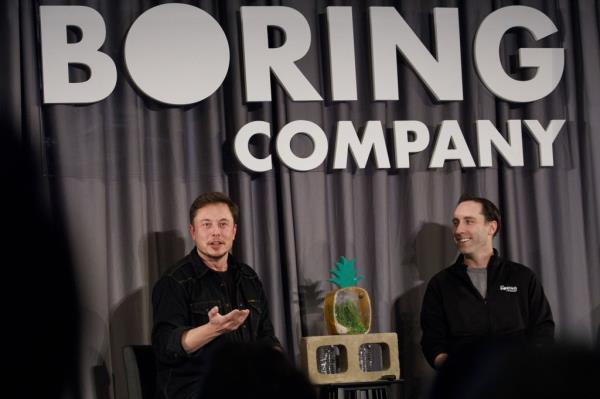 Elon Musk and Steve Davis at a Boring Company event in 2018 in front of "Boring Company" backdrop.