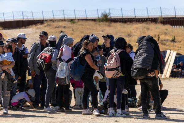 Dozens of migrants wait for border agents after crossing the border into the San Diego sector.