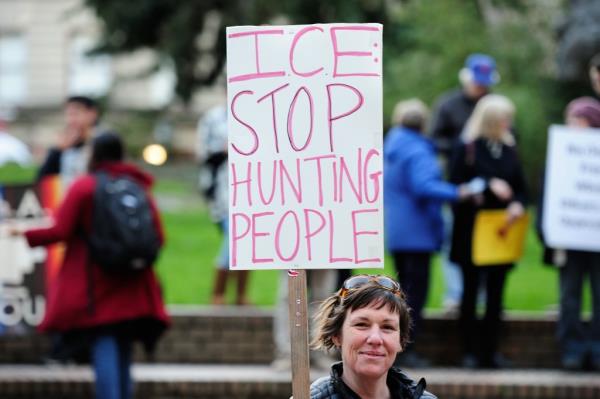 A woman holds a sign  that reads "ICE stop hunting people" against Immigration and Customs Enforcement raids during a rally in support of immigrant justice and the Deferred Action for Childhood Arrivals (DACA) Obama-era immigration policy in Portland, Oregon, United States on February 28, 2017. 