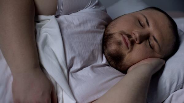 Closeup of chubby man sleeping peacefully, relaxing on comfortable mattress