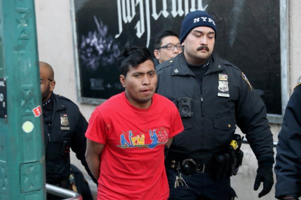 Police walk the Guatemalan migrant accused of burning a subway rider to death in handcuffs.