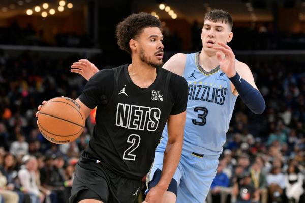 Brooklyn Nets forward Cam Johnson dribbling the basketball ahead of Memphis Grizzlies forward Jake LaRavia during a basketball game