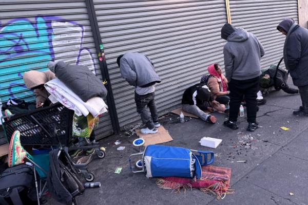 People leaned up against a wall at the intersection of East 149th Street and Third Avenue on Nov. 12, 2024.