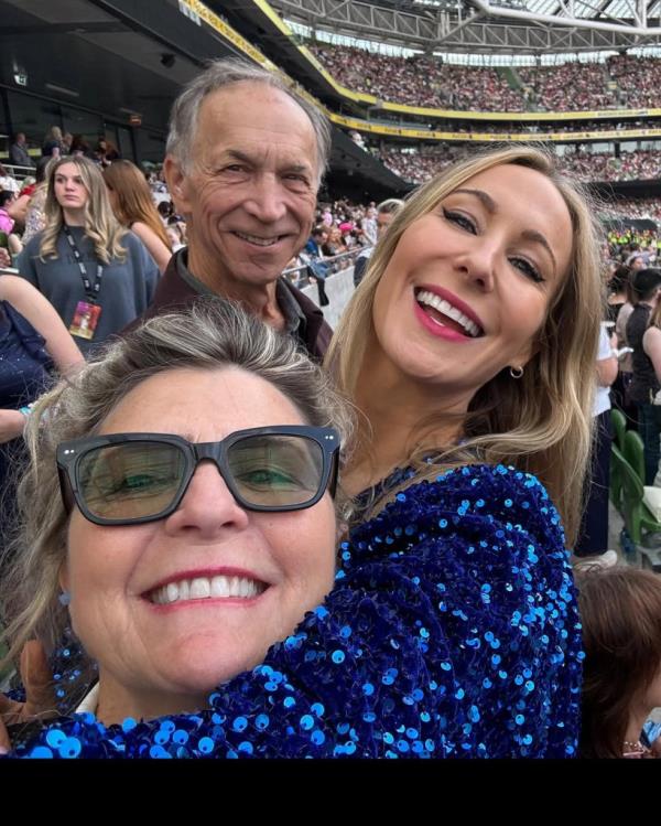 Nikki Glaser taking a selfie at a Taylor Swift co<em></em>ncert in a stadium