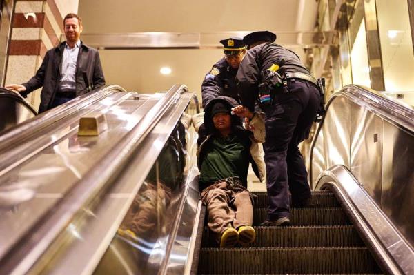 Members of the New York City Police Department(NYPD) and employees with the New York City Department of Homeless Services (DHS) assist a woman who collapsed on an escalator at the 34th Street-Herald Square subway station.