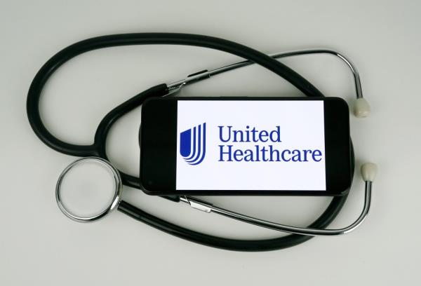 United Healthcare logo displayed on a smartphone screen, surrounded by medical props