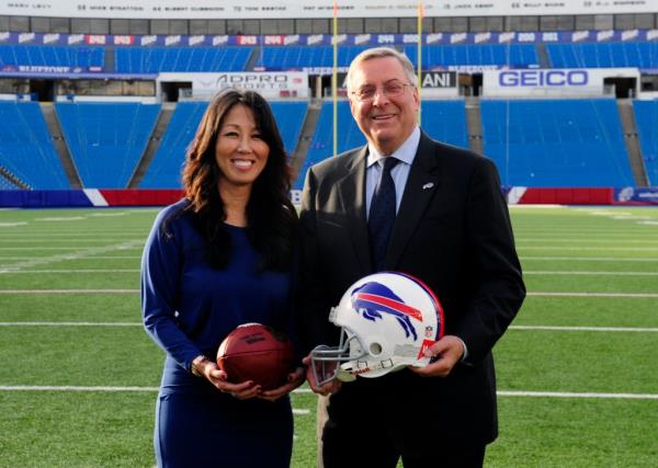 Kim and Terry Pegula standing on a football field