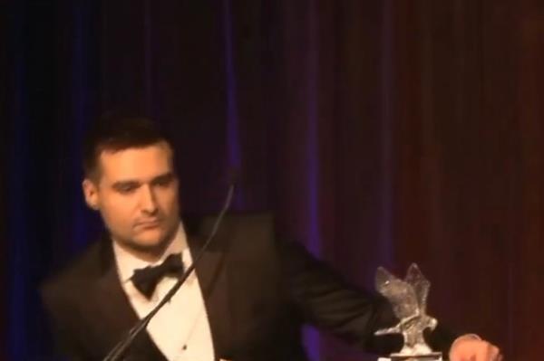 Trump advisor Alex Bruesewitz in a suit and bow tie collapsing on stage during a speech at New York Young Republican Club gala